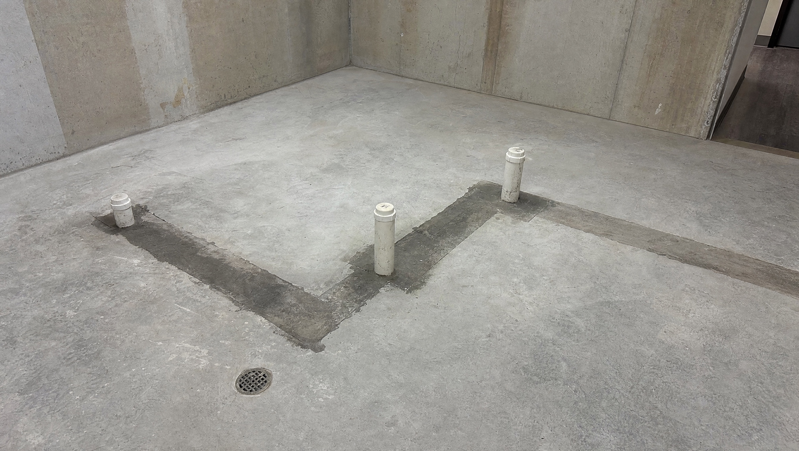 Rear service area. Sanitary rough-in and the slab where the required exterior interceptor lands.