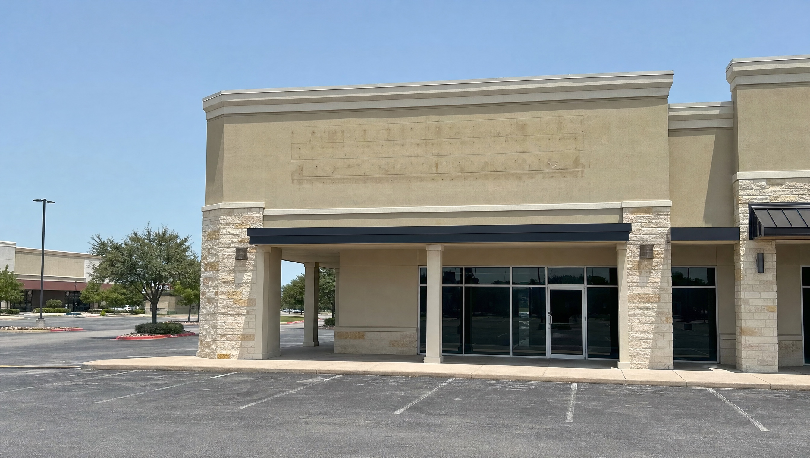 A vacant end-cap retail suite with a covered walkway and a dark storefront.